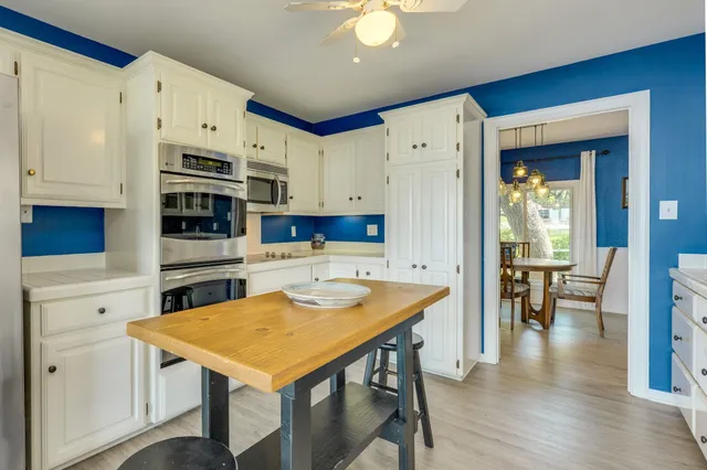 a kitchen with stainless steel appliances granite countertop a stove refrigerator and a dining table with wooden floor