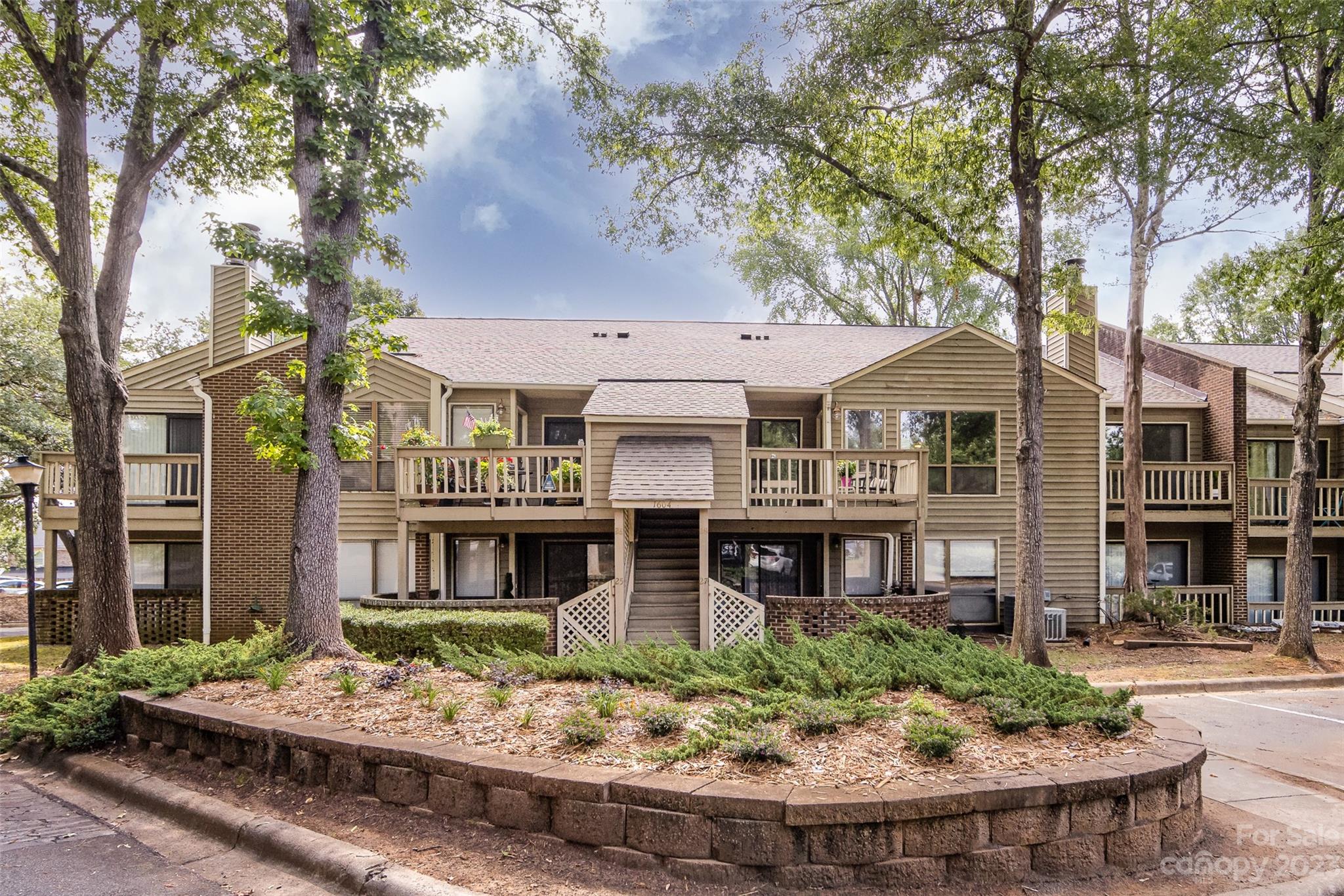 1604 Sharon Road West, Unit 27 Charlotte, NC 28210 - Photo 1 of 28 a front view of a residential apartment building with a yard and potted plants