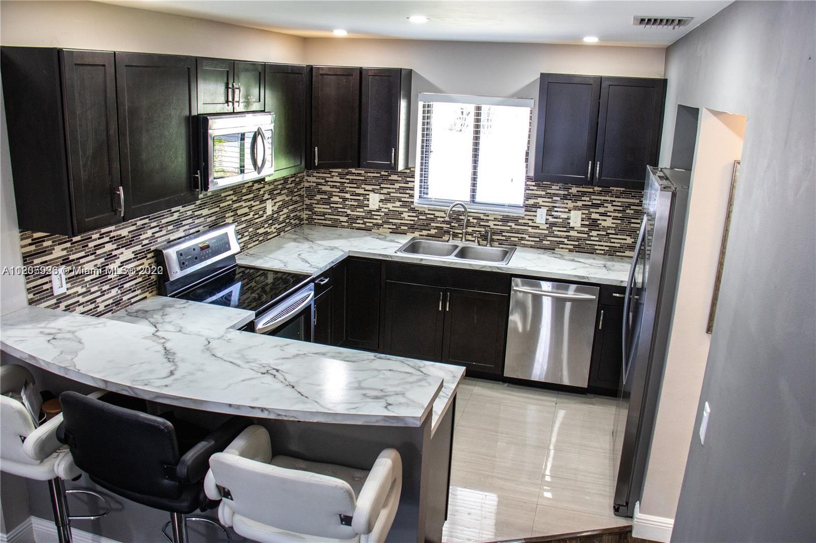 9300 Southwest 132nd Street, Unit 9300 Miami, FL 33176 - Photo 4 of 13 a kitchen with stainless steel appliances kitchen island granite countertop a sink stove and refrigerator