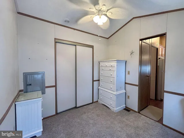 an empty room with chandelier fan and closet