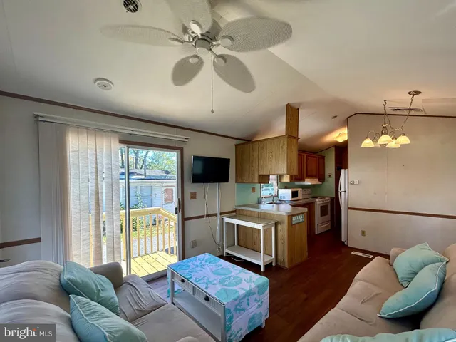 a living room with stainless steel appliances granite countertop furniture a fireplace a flat screen tv and a large window