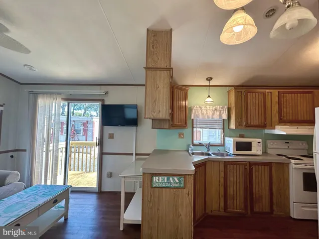 a kitchen with granite countertop a refrigerator a stove a sink dishwasher and wooden cabinets with wooden floor