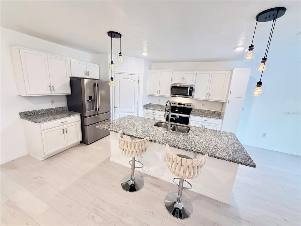 2731 House Finch Road Harmony, FL 34773 - Photo 26 of 95 a kitchen with stainless steel appliances granite countertop a sink refrigerator and cabinets