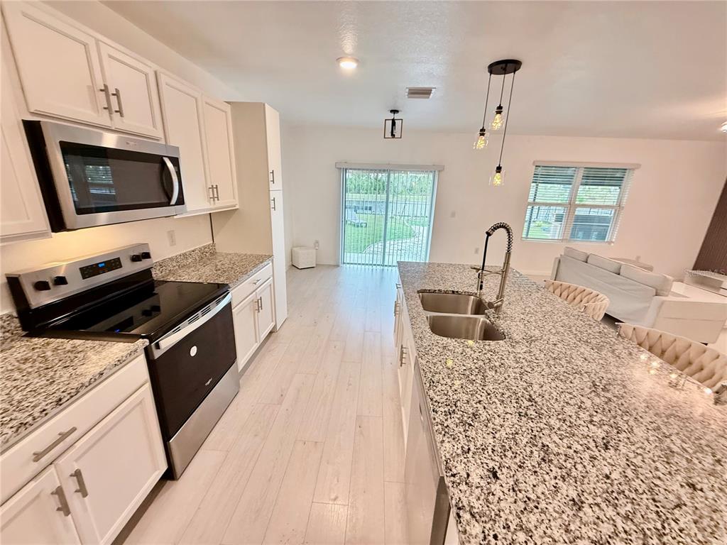 2731 House Finch Road Harmony, FL 34773 - Photo 27 of 95 a kitchen with granite countertop a stove a sink and a microwave
