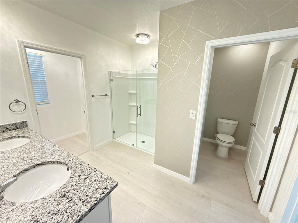 2731 House Finch Road Harmony, FL 34773 - Photo 45 of 95 a bathroom with a granite countertop sink a toilet and shower