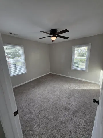 an empty room with windows and fan