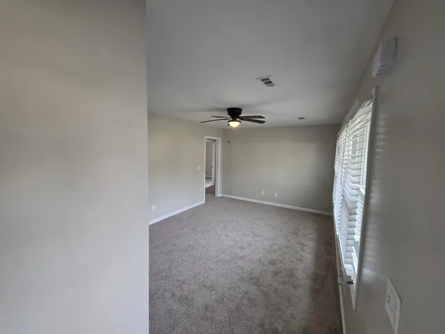an empty room with a chandelier fan and windows