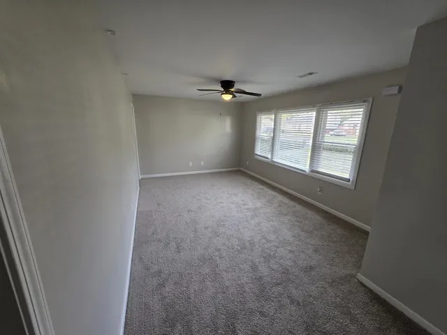 an empty room with windows and ceiling fan