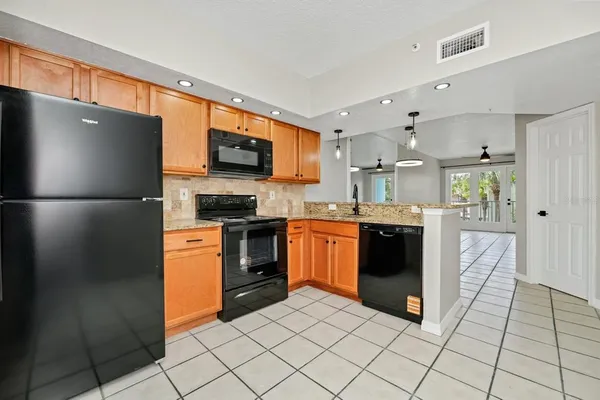 a kitchen with stainless steel appliances granite countertop a stove top oven a sink dishwasher and microwave with wooden floor