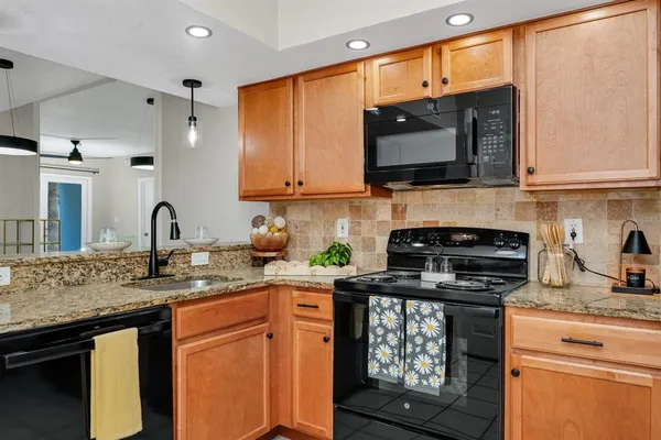 a kitchen with stainless steel appliances granite countertop a refrigerator a stove a sink and a microwave