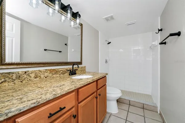 a bathroom with a granite countertop toilet sink and mirror
