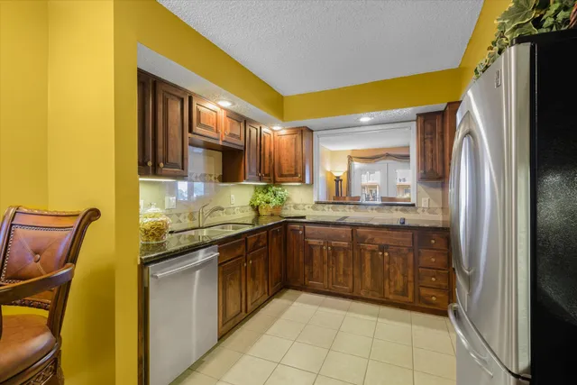 a kitchen with stainless steel appliances granite countertop a sink and a refrigerator