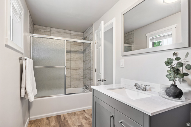 75 East 100 North Midway, UT 84049 - Photo 13 of 43 Wood-finish flooring, full bathtub with sliding glass doors, tiled shower surround, framed mirror, and a vanity with a white countertop and integrated sink