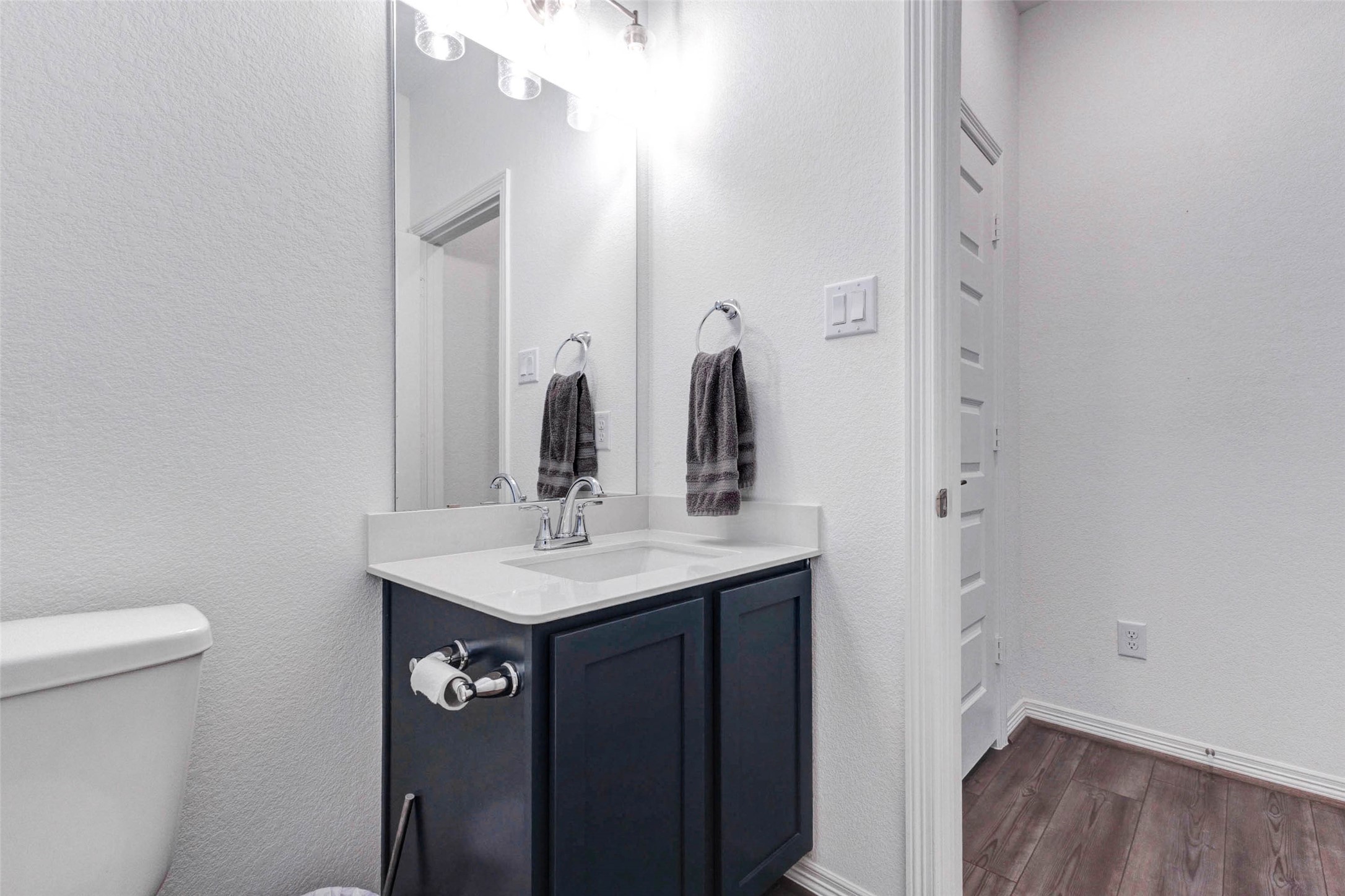 32418 Fly Fish Way Fulshear, TX 77441 - Photo 21 of 40 The conveniently located powder bath features the same bold dark cabinetry and crisp white countertop found throughout the home, keeping the design cohesive and polished for guests.