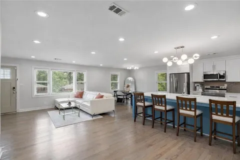 a living room with furniture kitchen view and a large window
