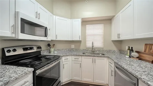 a kitchen with granite countertop cabinets stove top oven and sink