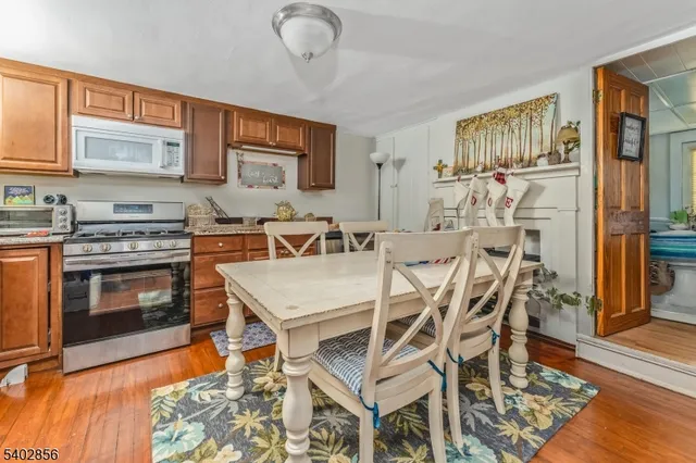 a dining hall with stainless steel appliances a stove a sink dishwasher a dining table and chairs with wooden floor