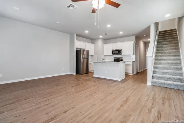 a view of a kitchen with wooden floor and a ceiling fan