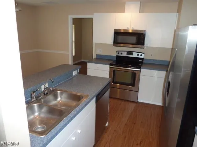 a kitchen with kitchen island a sink appliances and wooden floor