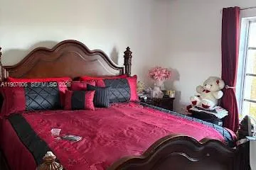 a bedroom with a bed purple white bedspread and pillows