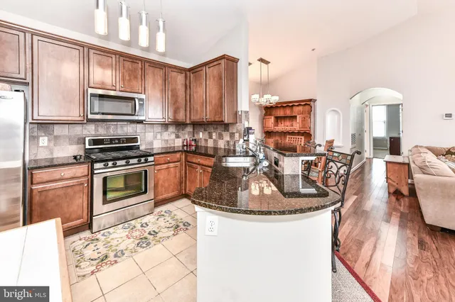 a kitchen with stainless steel appliances granite countertop a stove a sink and a microwave