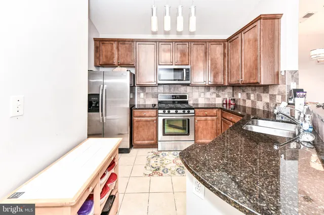 a kitchen with stainless steel appliances granite countertop a stove a sink and a microwave