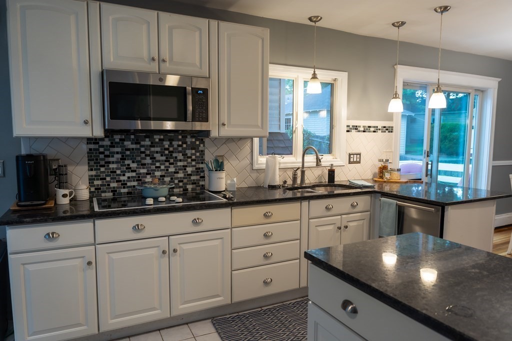 12 Newcastle Road Peabody, MA 01960 - Photo 8 of 35 a kitchen with white cabinets a sink and a stove with wooden floor