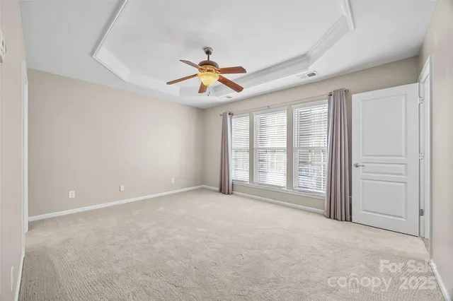 an empty room with windows and ceiling fan