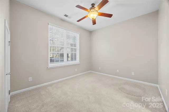 an empty room with windows and chandelier fan