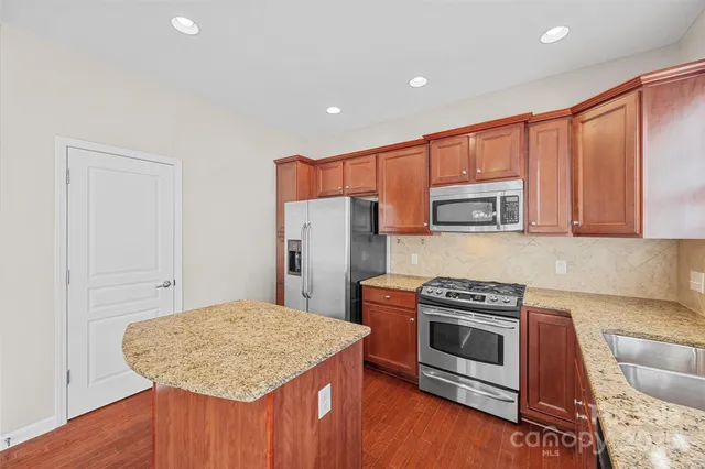 a kitchen with stainless steel appliances granite countertop a stove a sink dishwasher and a refrigerator