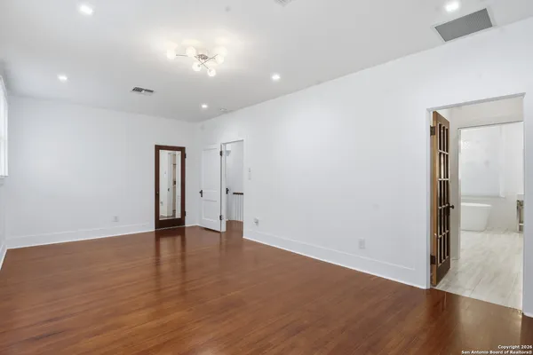 an empty room with windows fireplace and wooden floor
