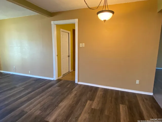 an empty room with windows and chandelier fan