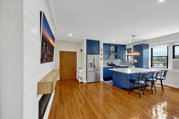 a living room with stainless steel appliances a dining table wooden floor and a window