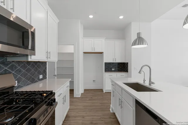 a kitchen with granite countertop white cabinets and stainless steel appliances