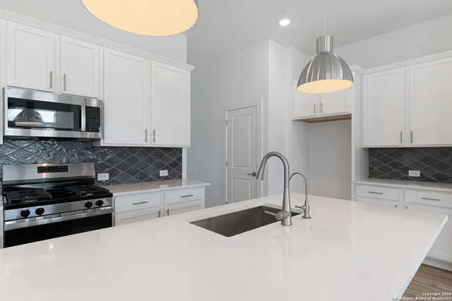 a kitchen with stainless steel appliances granite countertop a sink a stove a microwave and cabinets