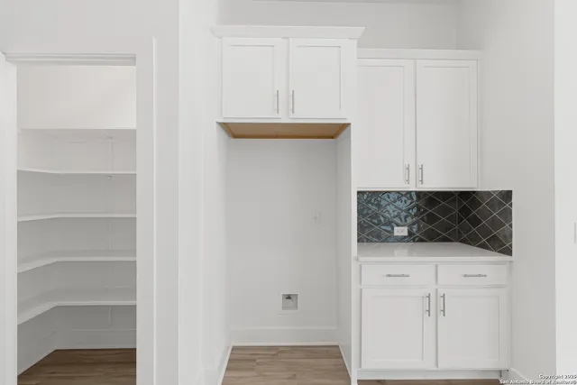 a view of a hallway with wooden floor and a bathroom
