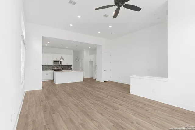 a view of kitchen and empty room with wooden floor