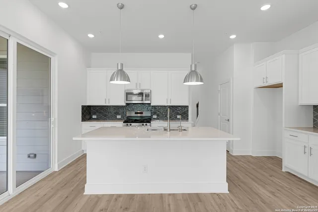 a kitchen with kitchen island granite countertop a sink and a stove top oven
