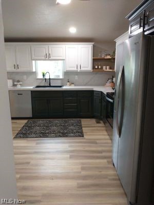 1990 Tabor Ridge Road Northeast New Philadelphia, OH 44663 - Photo 5 of 8 Kitchen featuring range, backsplash, light countertops, light hardwood floors, dishwasher, and stainless steel fridge