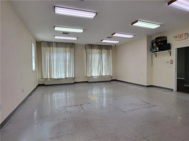 an empty room with windows and fireplace