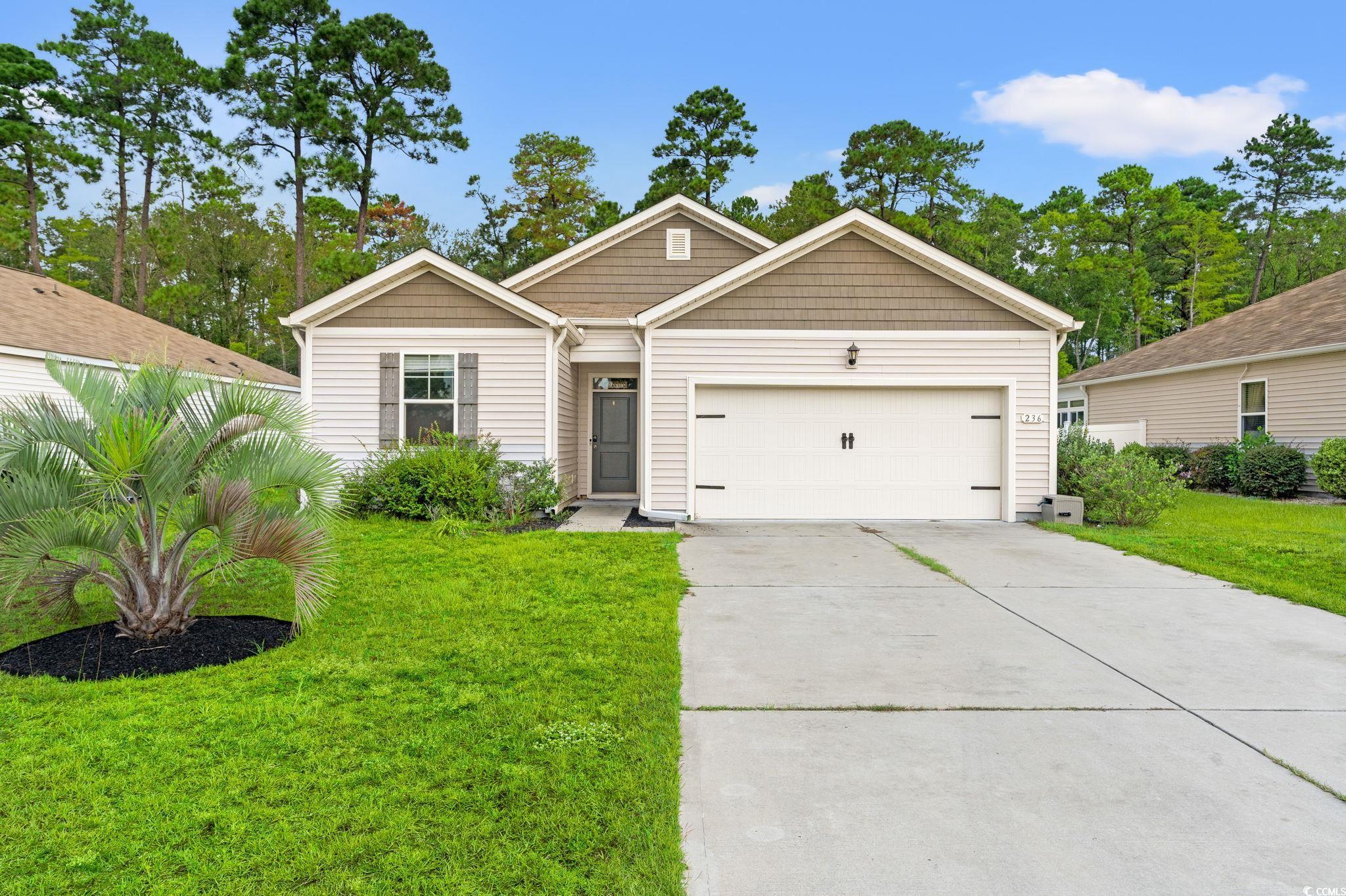 View of front of property featuring concrete driveway, a garage, and a front yard