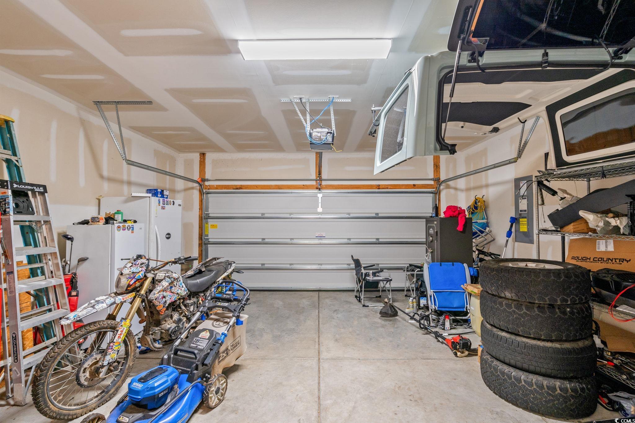 236 Legends Village Loop Myrtle Beach, SC 29579 - Photo 16 of 23 Garage with freestanding refrigerator, electric panel, and a garage door opener