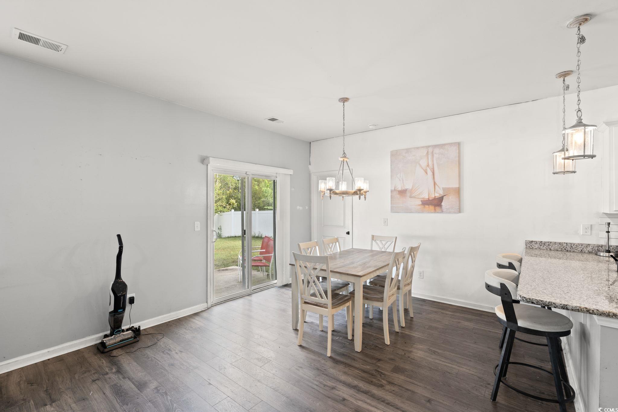 Dining room with dark wood finished floors and a chandelier