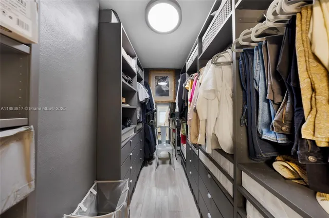 a view of walk in closet with clothes and shoes