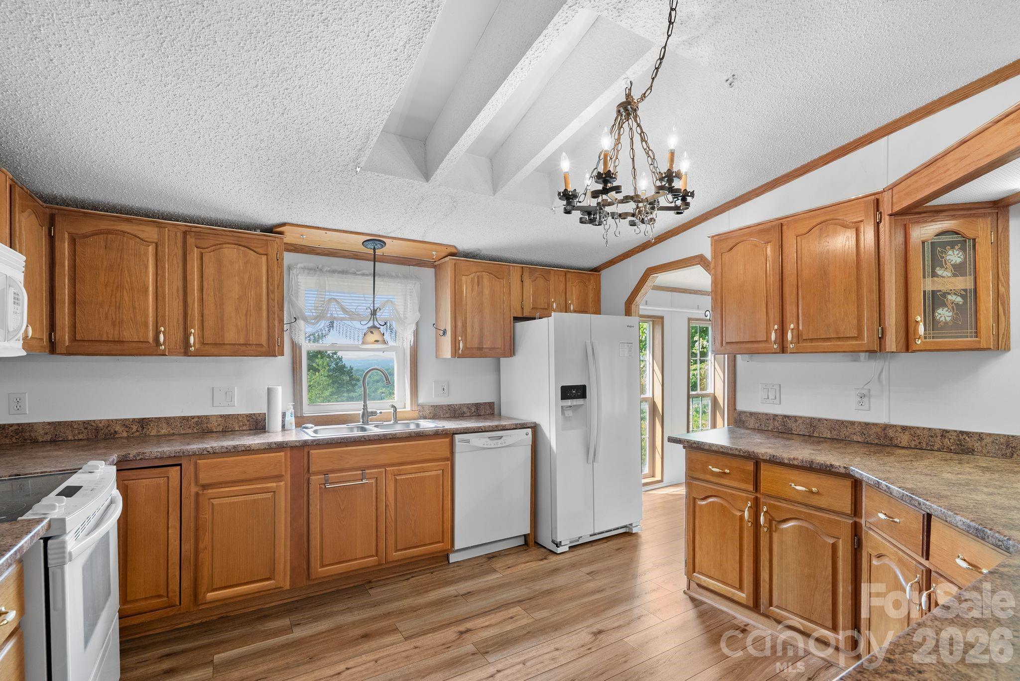 133 Spivey Mountain Road Asheville, NC 28806 - Photo 9 of 40 a kitchen with stainless steel appliances granite countertop a refrigerator a sink dishwasher a stove and white countertops with wooden floor