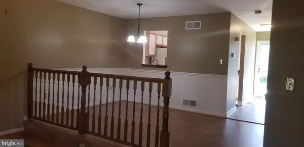 a view of a hallway with wooden floor and a dining room