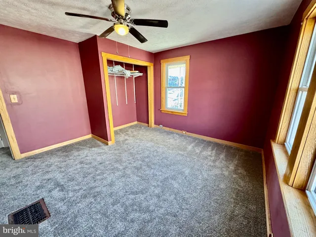 an empty room with windows and fan