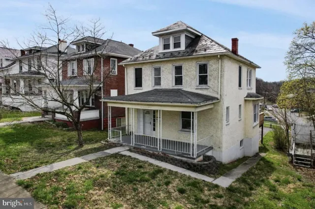 a view of a white house next to a yard with big trees