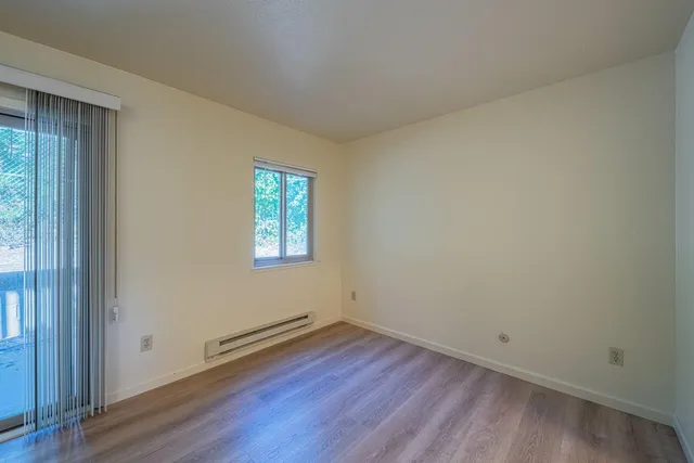 an empty room with wooden floor and windows