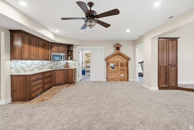 672 Perry Hollow Drive Mapleton, UT 84664 - Photo 75 of 106 Spacious room featuring a curved wet bar with wood-finish cabinetry, light-colored countertops, subway tile backsplash, and an undermount sink
